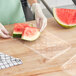 A person holding a slice of watermelon on a clear plastic tray.