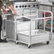 A person pushing a Regency aluminum double bun pan truck with a large stack of trays.