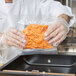 A person in a professional kitchen using an ARY VacMaster zipper vacuum packaging bag to hold food.