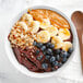 A bowl of Pitaya Foods acai berry pieces with bananas and nuts.