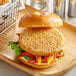 A Daring Foods plant-based chicken patty on a wooden board with a basket of fries.