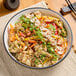 A bowl of rice with vegetables and salted almond butter on a table.