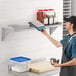 A man using a digital scale to measure ingredients on a Regency stainless steel wall shelf.