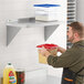 A man holding a container of food on a Regency stainless steel wall shelf.