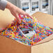 A hand reaching out to a box with colorful shredded paper.
