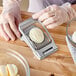 A hand using a Westmark egg slicer to cut a hard-boiled egg.