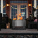 A BREEO stainless steel fire pit on a table on a patio.