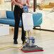 A man using a Lavex Pro rectangular floor machine with a white solution tank to clean a floor.