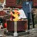 A BREEO stainless steel fire pit on a patio with a chair and a blanket.