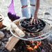 A person cooking mussels on a BREEO stainless steel grill grate over a fire.