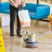 A man using a Lavex Pro floor scrubber to clean a hardwood floor.