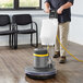 A man using a Lavex Pro heavy-duty floor machine with a solution tank to clean a floor.