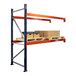 A blue and orange Interlake Mecalux heavy-duty bolted pallet rack with boxes on shelves.