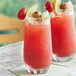 Two glasses of Dei Fratelli Tomato Juice with a straw on a table.