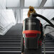 A woman using a NaceCare Solutions corded backpack vacuum cleaner on stairs.