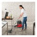 A woman using a NaceCare cordless canister vacuum to clean a wood floor.