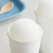 Two white cups of Philadelphia Water Ice Coconut Italian Ice on a white surface.