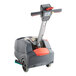 A NaceCare Solutions cordless walk behind floor scrubber with a red handle.