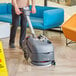 A man using a NaceCare cordless walk behind floor scrubber to clean a floor.