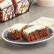 Two Ne-Mo's Bakery individually wrapped carrot cake squares on a plate.