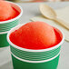 A red and green cup with a round ball of red Philadelphia Water Ice in it.