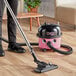 A person using a NaceCare corded canister vacuum with AST2 combination floor toolkit to clean hardwood floors.