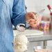 A person using a Choice stainless steel ladle to scoop ice cream into a bowl.