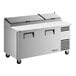 A stainless steel two-door refrigerated pizza prep table with a white cutting board and top storage compartments.