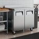 A stainless steel worktop refrigerator with two doors and a backsplash, designed for commercial kitchen use.
