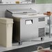 A stainless steel refrigerated pizza prep table with a single door and a white cutting surface on top.