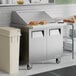 A stainless steel two-door mega top refrigerated sandwich prep table with a flat work surface and sandwiches on top.