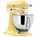 A close up of a yellow KitchenAid Artisan stand mixer with a bowl.