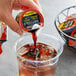 A person pouring a Java House Colombian Cold Brew coffee into a cup of ice.