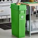 A woman in a chef's uniform using a Lavex lime green compost receptacle to throw away fruit.