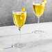 Two Della Luce Aurora Nick and Nora glasses filled with yellow liquid.