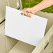 A hand placing a white CaterGator divider in a cooler.