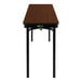 A National Public Seating Montana walnut plywood folding table with black legs.