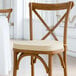 A Lancaster Table & Seating wooden chair with a tan cushion tied to the seat and back.