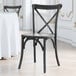 A Lancaster Table & Seating black outdoor cross back chair with a wooden seat and back.