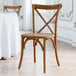 A Lancaster Table & Seating Vineyard Series Barrel Brown outdoor cross back chair at a table.