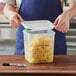 A person opening a plastic Araven food storage container with pineapple chunks inside.