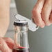 A hand uses the Franmara key-shaped bottle opener to open a bottle of liquid.