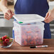 A man holding an Araven translucent square plastic container filled with strawberries.