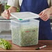 A man holding an Araven translucent plastic food storage container with green vegetables inside.