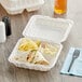 A white Choice plastic hinged take-out container with a sandwich, chips, and a drink.