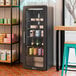 A black refrigerated glass door merchandiser with LED lighting, featuring multiple shelves for displaying food and beverages.