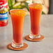 Two glasses of orange liquid with Torani Orange Flavoring Syrup on a table.