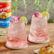 Two glasses of pink drinks with flowers and limes using Torani Elderflower Flavoring Syrup.