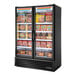A True glass door merchandiser freezer with full length doors full of food.