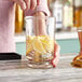 A person mixing a drink in an Acopa footed cocktail stirring glass with a spoon.